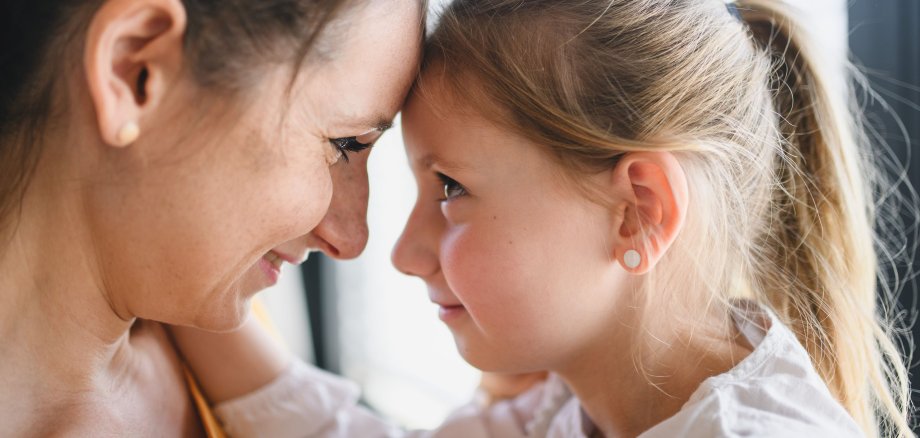 Mother and child indoors at home, hugging.